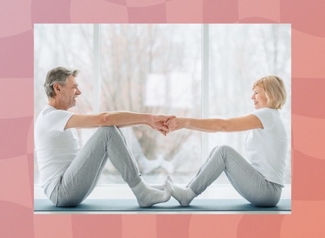 mature couple stretching together in bright living room in front of window