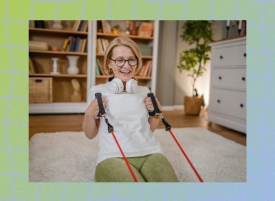 happy older woman with glasses doing resistance band floor exercise in living room