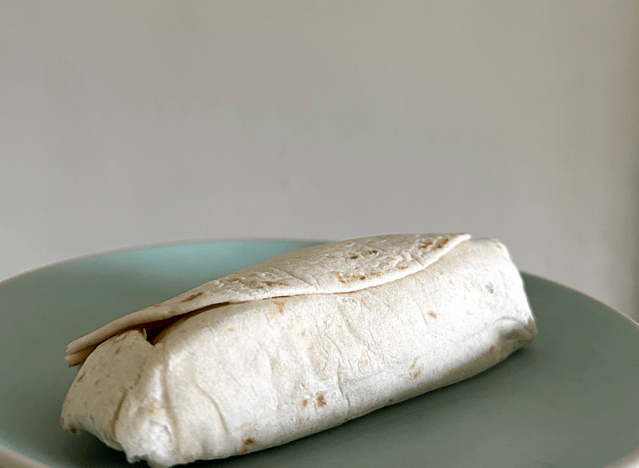 a mcdonalds breakfast burrito on a green plate. 
