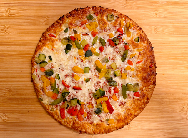 a cauliflower veggie pizza on a cutting board. 