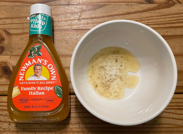 a bottle of newmans italian dressing with some in a bowl.