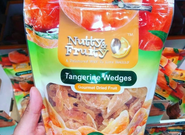 a hand holding nutty and fruity tangerine wedges in a bag.