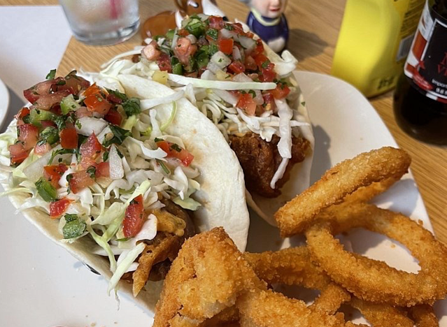 fish tacos and onion rings on a plate.