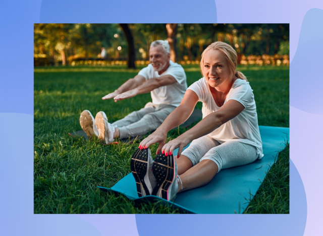 senior couple doing leg stretches on yoga mats in park on sunny day