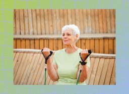senior woman in green t-shirt doing resistance band bicep curls in front of fence outdoors