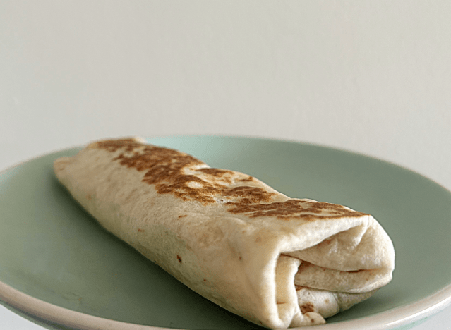 a taco bell breakfast burrito on a green plate. 