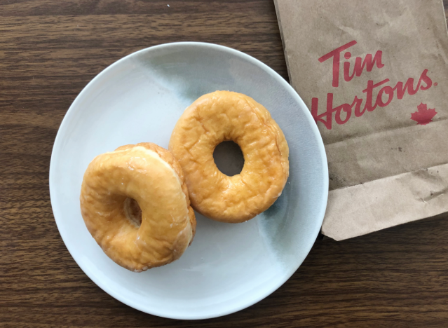 two glazed donuts on a plate with a tim horton's bag.