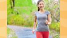 happy woman walking for exercise outdoors on lush, green trail