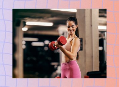 fit woman wearing tan sports bra and pink leggings doing dumbbell bicep curls at the gym