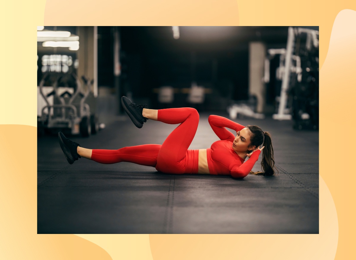 fit woman in red athletic attire doing bicycle crunches at the gym