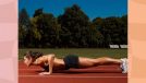 fit woman in black sports bra and shorts doing pushups outdoors on a track