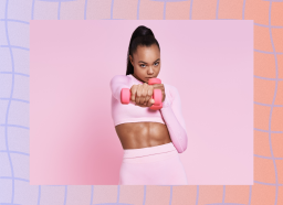 fit, focused woman in pink workout attire doing dumbbell exercise in front of pink backdrop