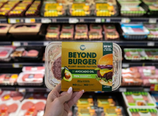 woman holding beyond meat's plant-based burger patties at the grocery store