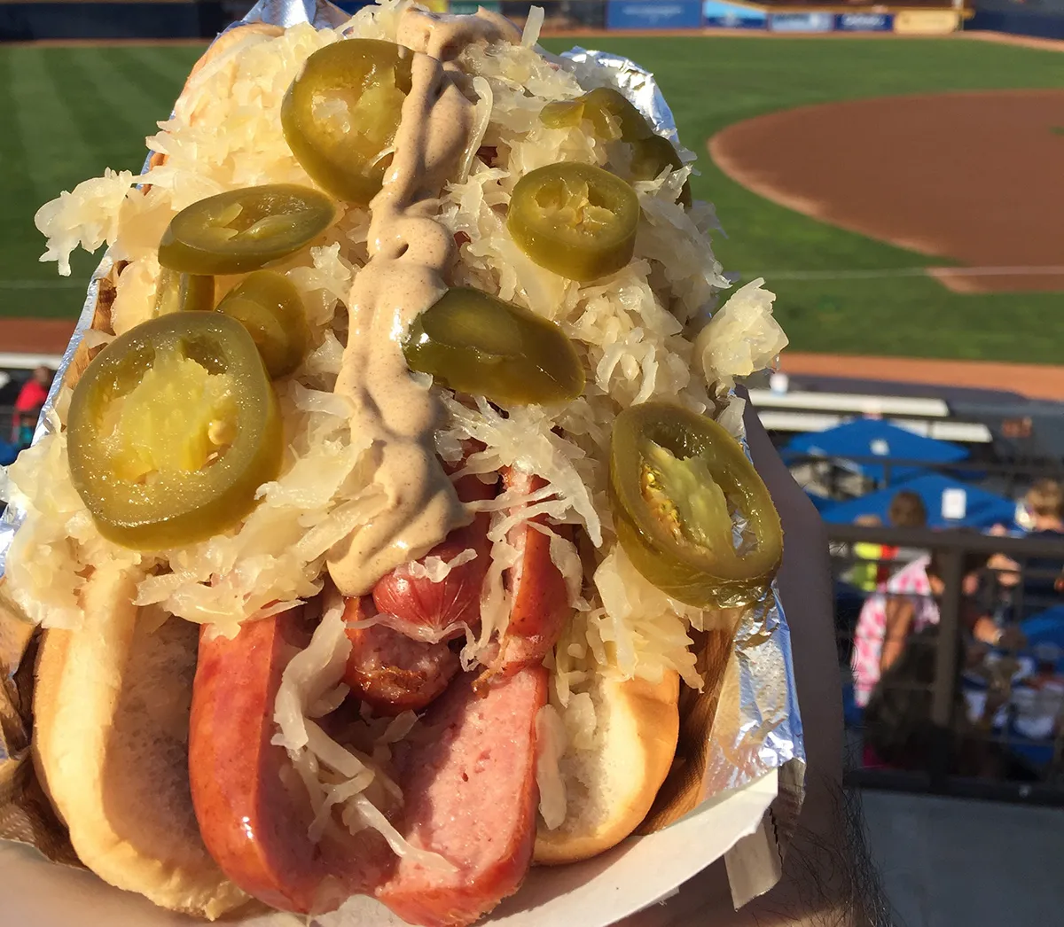 Hot dog loaded with toppings at a baseball park