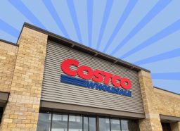 The storefront of a Costco warehouse set against a colorful background