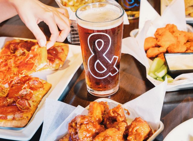 A pint of beer surrounded by plates of food at Dave & Buster's