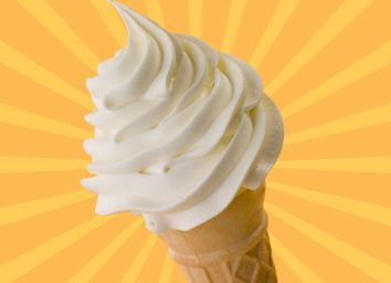 A vanilla soft serve ice cream cone set against a colorful background