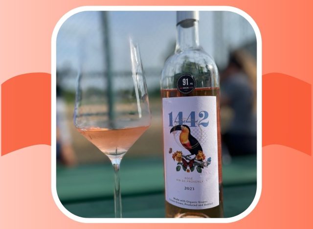 A bottle of 1442 Rosé Vin De Provence next to a glass of the pink-tinted wine.