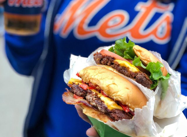 a jersey wearing mets fan holding a beer and burgers.