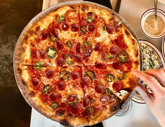 A pizza with sliced fresh jalapeno and pepperoni at Tiny Champions.