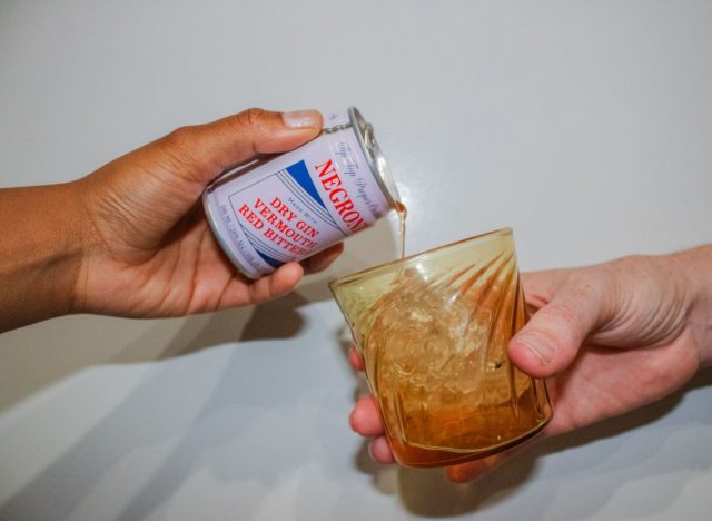 pouring a canned negroni into a glass