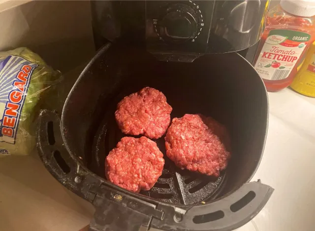 three hamburger patties in an air fryer