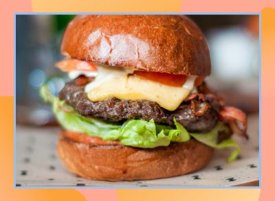 bacon cheeseburger with lettuce and tomato on a designed background