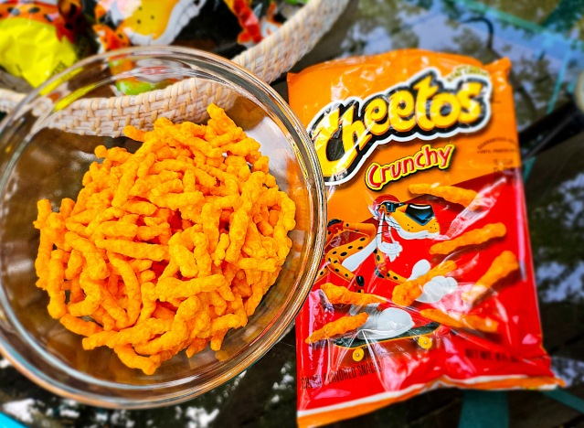 a bowl of crunchy cheetos next to a bag.