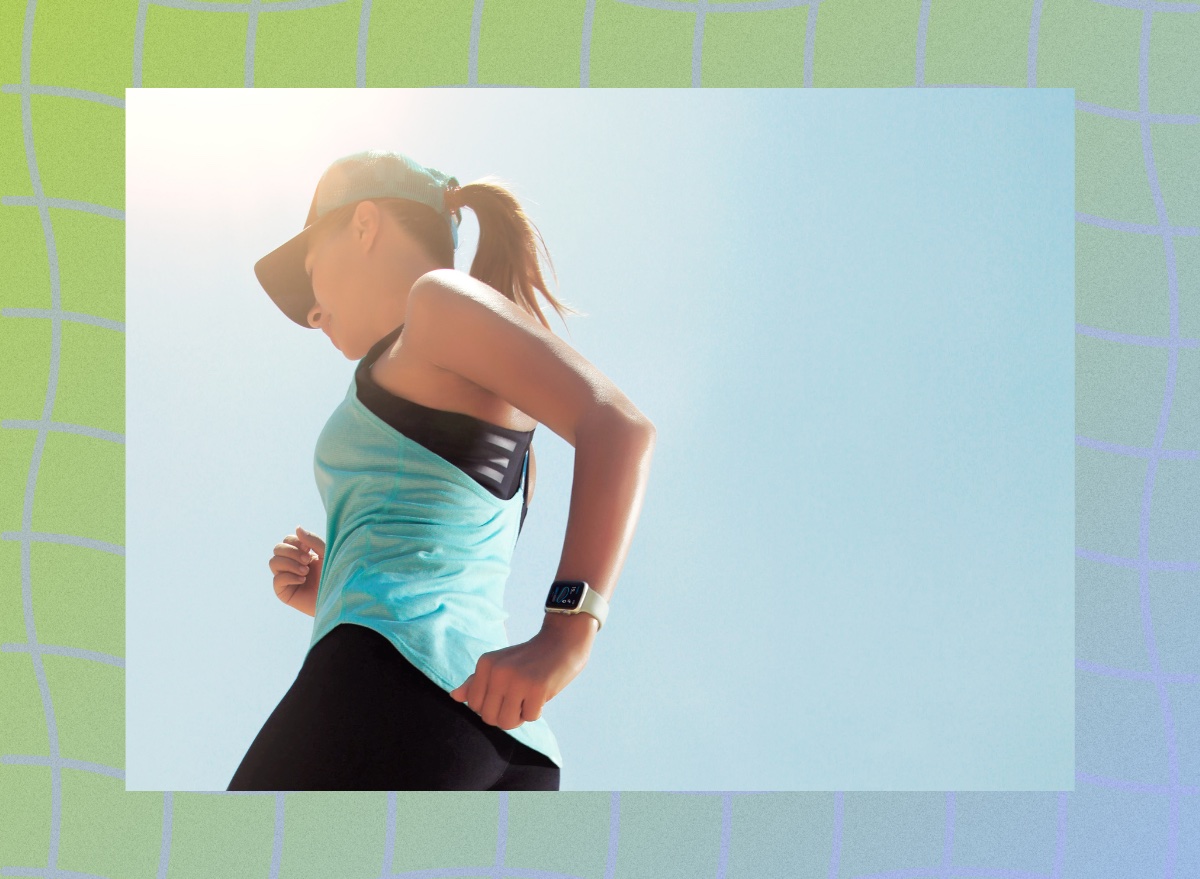 close-up of brunette woman in blue tank and baseball cap running outdoors under the sun