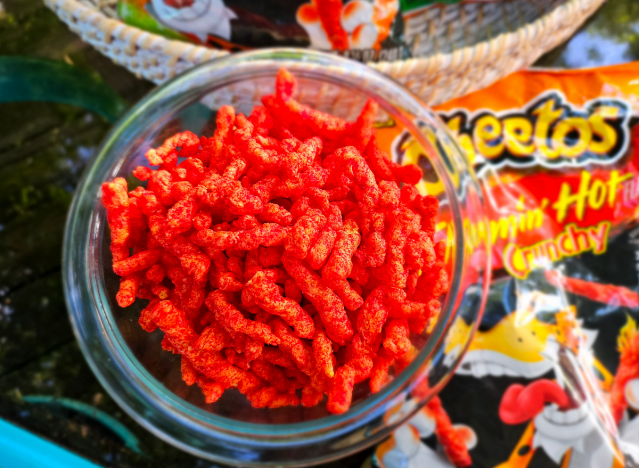 flamin hot cheetos in a bowl with a bag next to it 