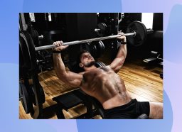 muscular, shirtless man doing barbell bench press at the gym