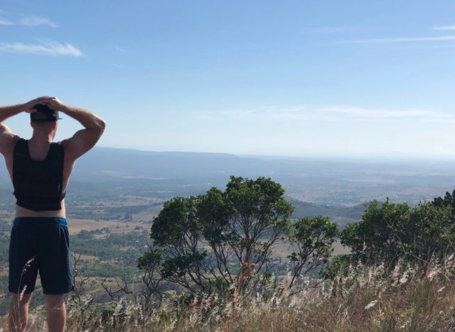 man wearing a weighted vest at the top of a mountain hike