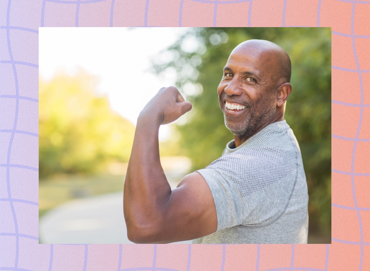 mature, happy man flexing his arm muscle outdoors during walking workout