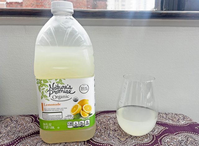 A bottle of Nature's Promise-brand lemonade next to a small glass of the beverage