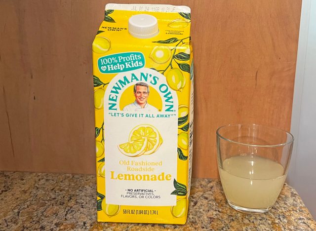 A carton of Newman's Own brand lemonade next to a small glass of the beverage.
