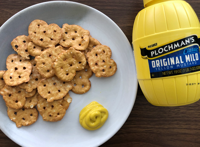 a bottle of plochmans mustard next to a plate of pretzels 
