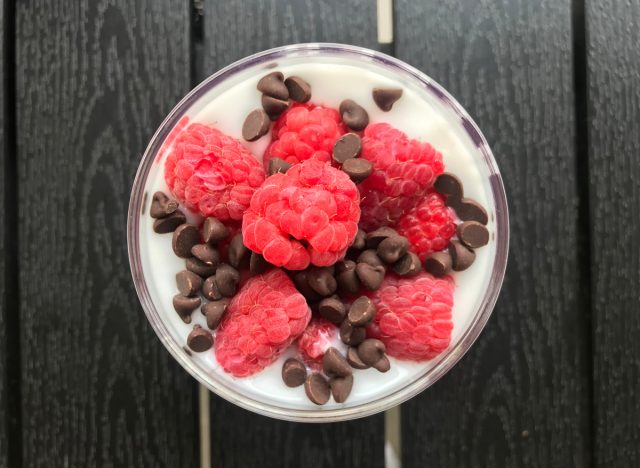 raspberries and chocolate chips on top of a cup of yogurt