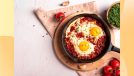shakshuka in skillet surrounded by tomatoes and chives