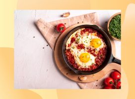 shakshuka in skillet surrounded by tomatoes and chives