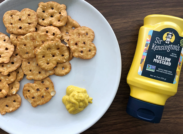 a bottle of sir kensington mustard next to pretzels on a plate 