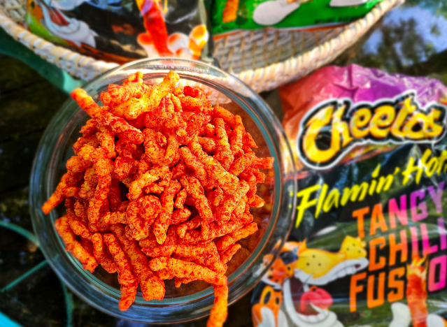 a bowl of tangy chili fusion cheetos next to a bag.