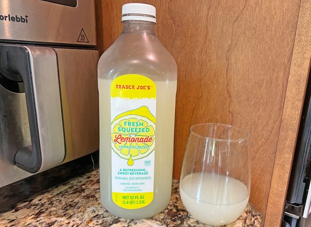 A bottle of Trader Joe's private-label lemonade next to a small glass of the beverage.