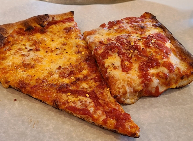 a slice of regular pizza next to a sicilian slice.