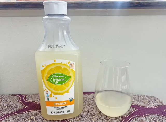 A bottle of Wegmans private-label lemonade next to a small glass of the beverage.