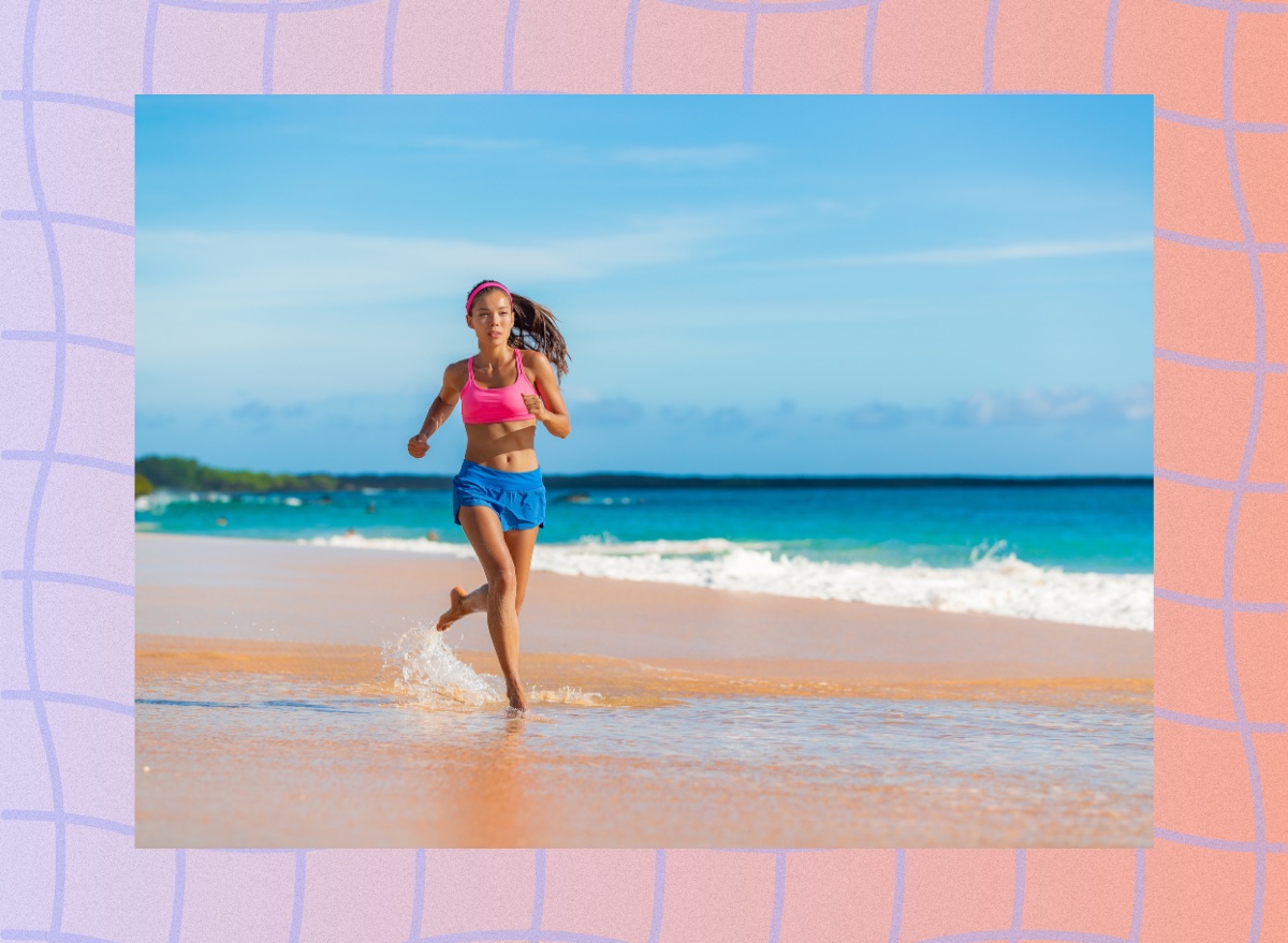 fit woman in pink sports bra and blue gym shorts running on a beach