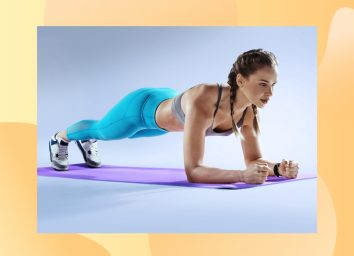 fit woman doing forearm plank on purple yoga mat