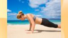 fit woman in sports bra and leggings doing pushups on sand at the beach by turquoise ocean water