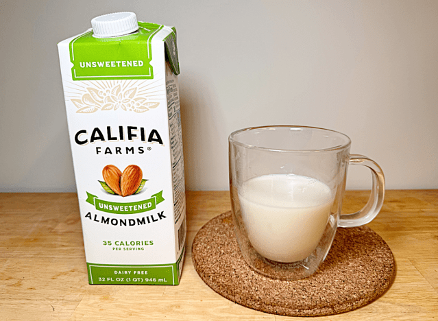 a container of califia almond milk next to a glass of almond milk 