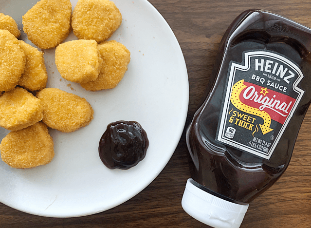 a bottle of heinz bbq sauce next to a plate of chicken nuggets 
