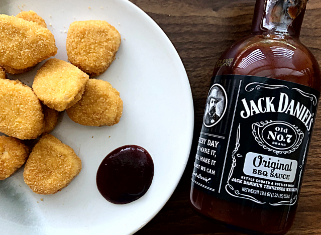 a bottle of jack daniels bbq sauce next to a plate of chicken nuggets